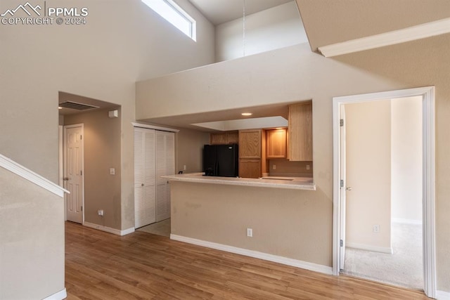 unfurnished living room with light wood-type flooring and a towering ceiling