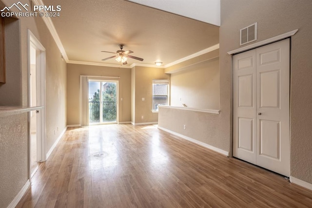 unfurnished living room featuring crown molding, visible vents, ceiling fan, wood finished floors, and baseboards