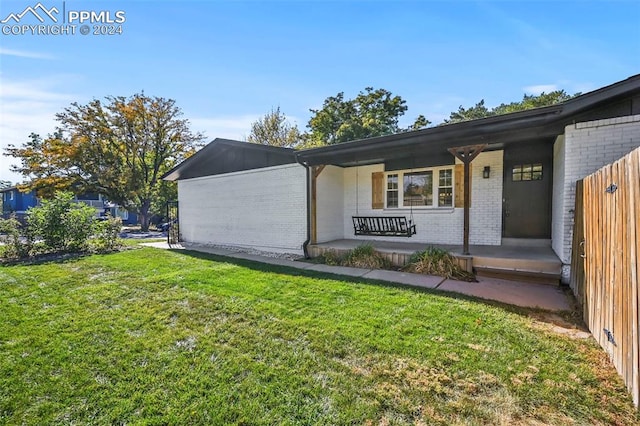 exterior space featuring a front lawn, a porch, and brick siding