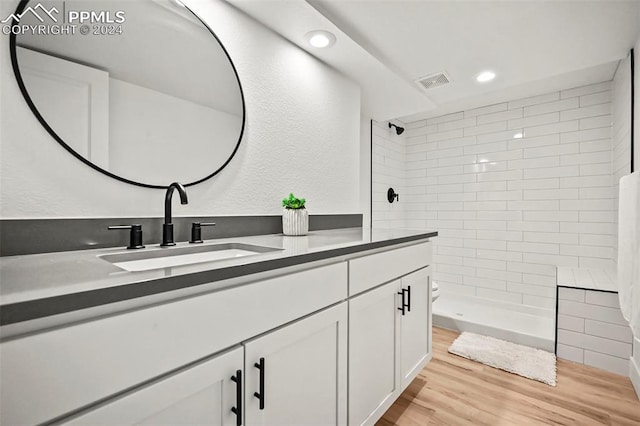 full bath featuring recessed lighting, wood finished floors, vanity, visible vents, and tiled shower