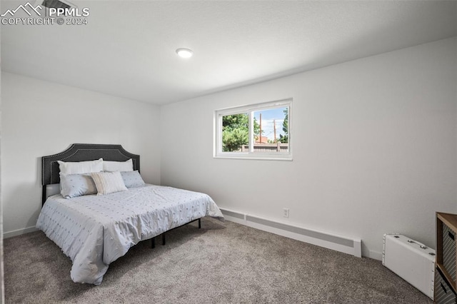 carpeted bedroom with a baseboard heating unit and baseboards