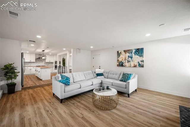 living area featuring baseboards, light wood-type flooring, visible vents, and recessed lighting