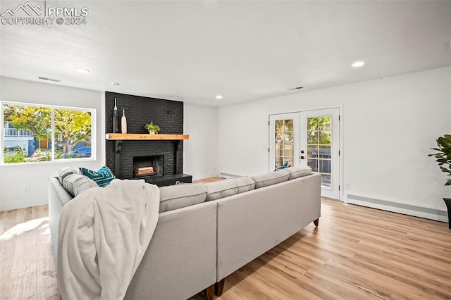 living area with light wood-style floors, a baseboard radiator, a wealth of natural light, and french doors