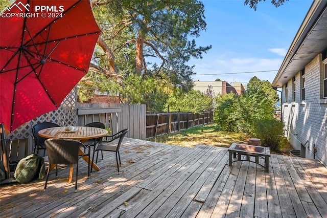 wooden terrace featuring outdoor dining space and a fenced backyard