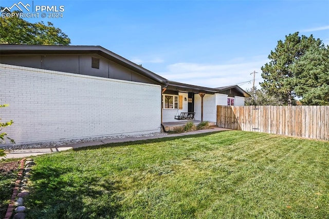 view of front of home with a front yard, fence, and brick siding