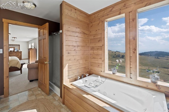 bathroom with separate shower and tub, plenty of natural light, and wooden walls