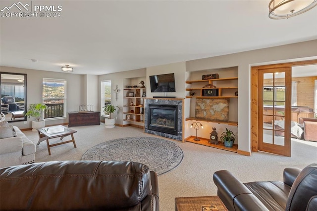 carpeted living room with a wealth of natural light, a high end fireplace, and built in shelves