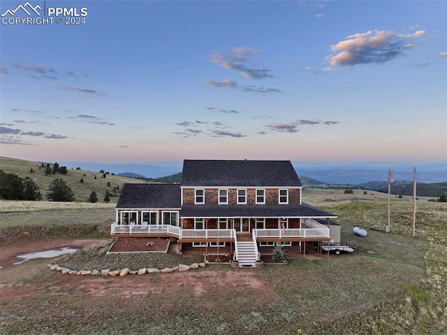 view of front facade with a wooden deck and a rural view