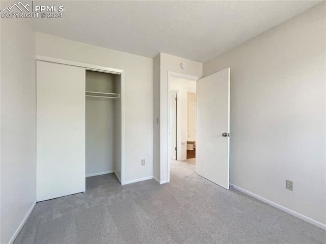 unfurnished bedroom featuring a closet, a textured ceiling, and carpet flooring