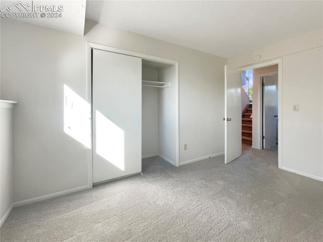 unfurnished bedroom featuring light carpet and a closet