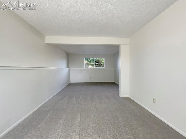 carpeted empty room featuring a textured ceiling