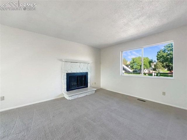 unfurnished living room featuring carpet flooring, a fireplace, and a textured ceiling