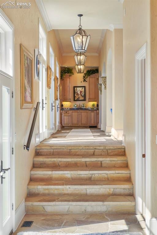 stairs with a notable chandelier, rustic walls, and crown molding