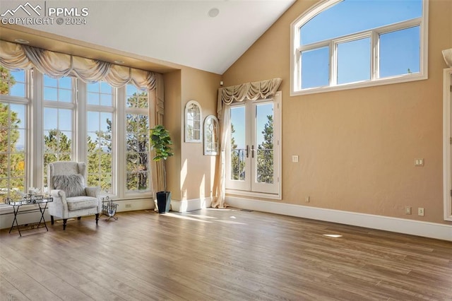 unfurnished room with high vaulted ceiling, hardwood / wood-style flooring, and french doors