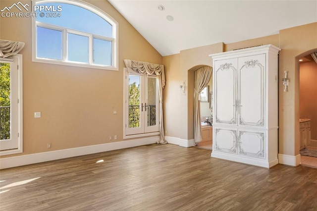 foyer entrance with high vaulted ceiling, a wealth of natural light, and wood-type flooring