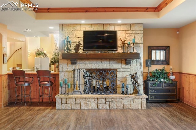 living room with a raised ceiling, a fireplace, wooden walls, and dark hardwood / wood-style floors