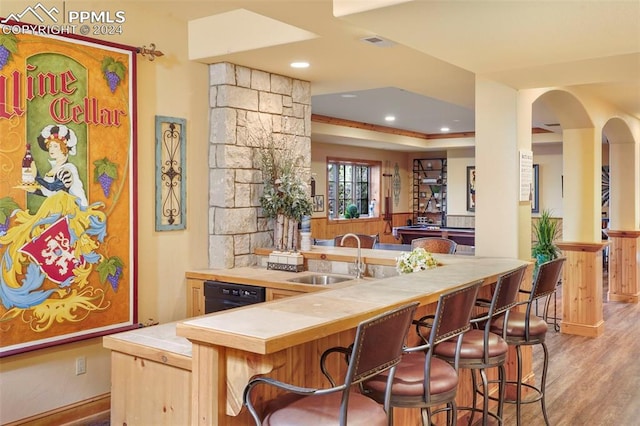 bar featuring dishwasher, light brown cabinets, light hardwood / wood-style flooring, tile counters, and sink