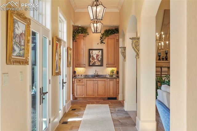 bar with hanging light fixtures, crown molding, sink, and french doors