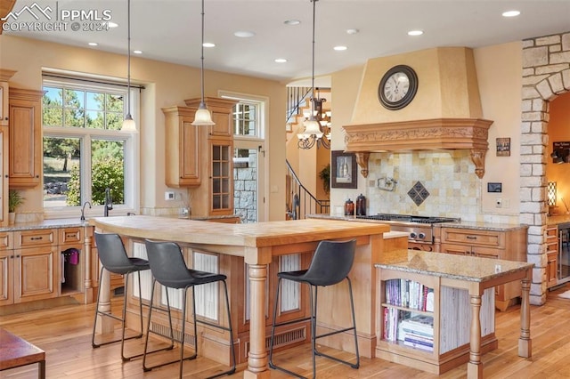 kitchen with light wood-type flooring, a chandelier, a kitchen island, and a breakfast bar area