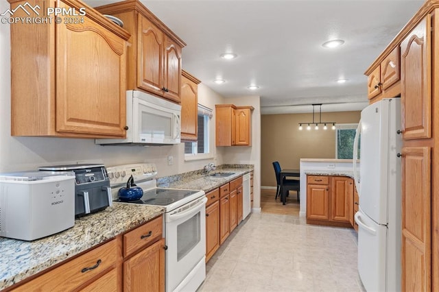 kitchen featuring a sink, white appliances, recessed lighting, pendant lighting, and light stone counters