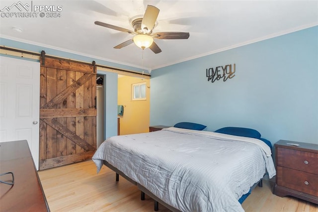 bedroom featuring a ceiling fan, wood finished floors, ornamental molding, and a barn door