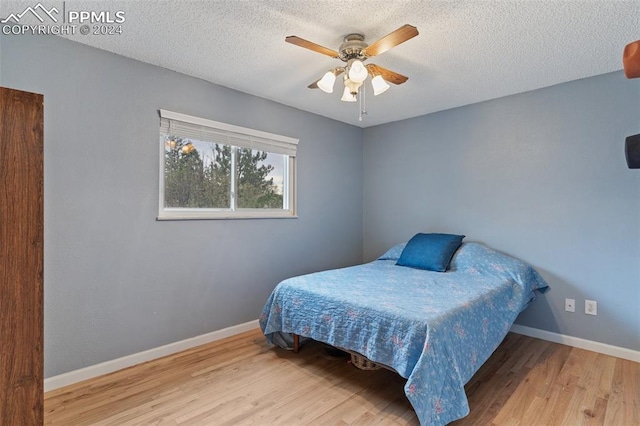 bedroom with a textured ceiling, wood finished floors, ceiling fan, and baseboards