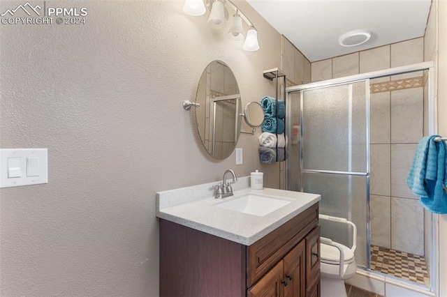 bathroom featuring toilet, a shower stall, vanity, and a textured wall