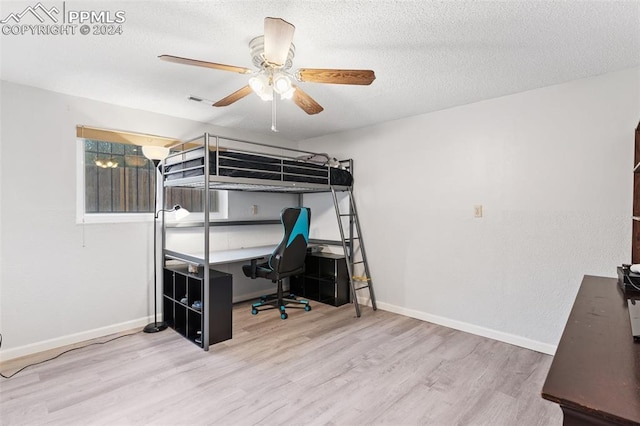 bedroom featuring ceiling fan, baseboards, a textured ceiling, and wood finished floors