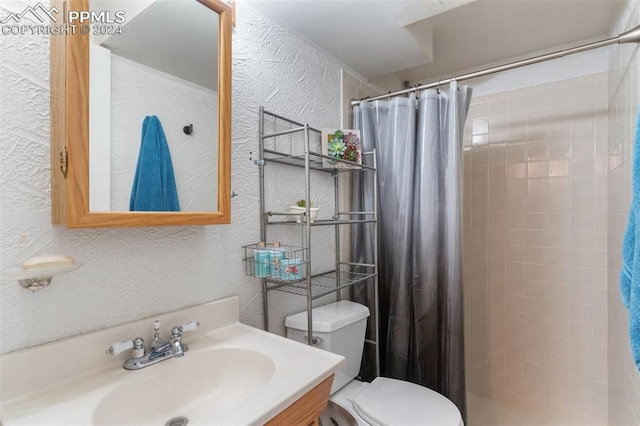 full bathroom with a tile shower, toilet, vanity, and a textured wall