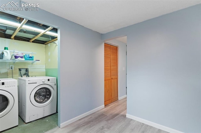laundry room with baseboards, light wood-style flooring, washer and clothes dryer, and laundry area