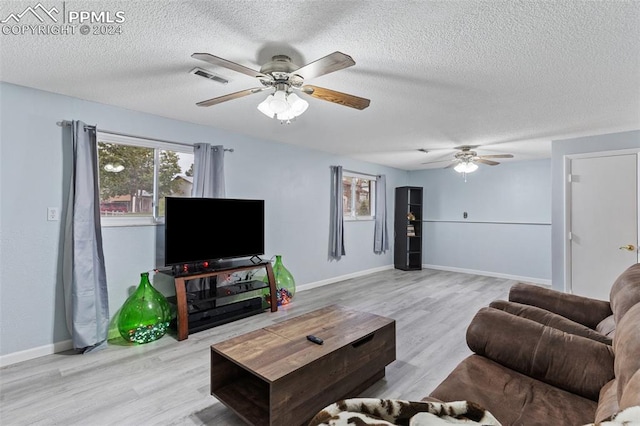living room featuring plenty of natural light, visible vents, a ceiling fan, and wood finished floors