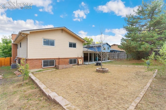 back of property with brick siding, a fenced backyard, a chimney, and an outdoor fire pit