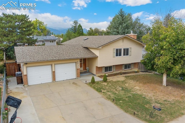 tri-level home featuring brick siding, a shingled roof, a garage, and concrete driveway