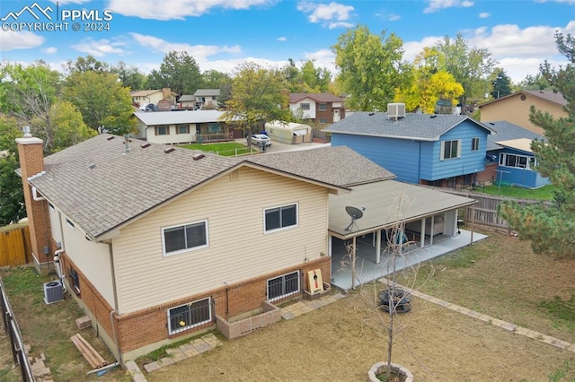 back of house featuring central AC, a fenced backyard, brick siding, a residential view, and roof with shingles