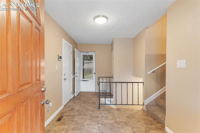 hall with visible vents, baseboards, stone finish floor, and stairs