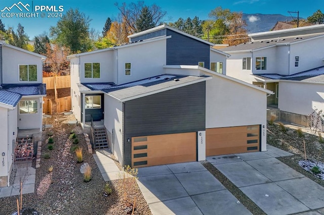 view of front of property with a garage, driveway, fence, and stucco siding