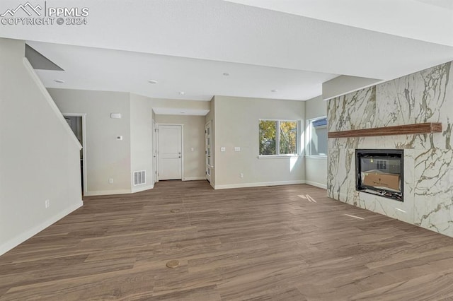 unfurnished living room with visible vents, a fireplace, baseboards, and wood finished floors