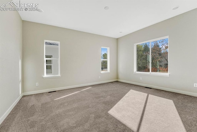 carpeted spare room featuring visible vents and baseboards