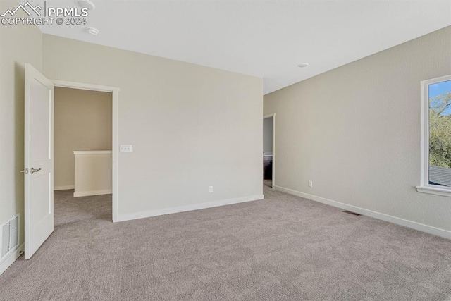 spare room with light carpet, visible vents, and baseboards