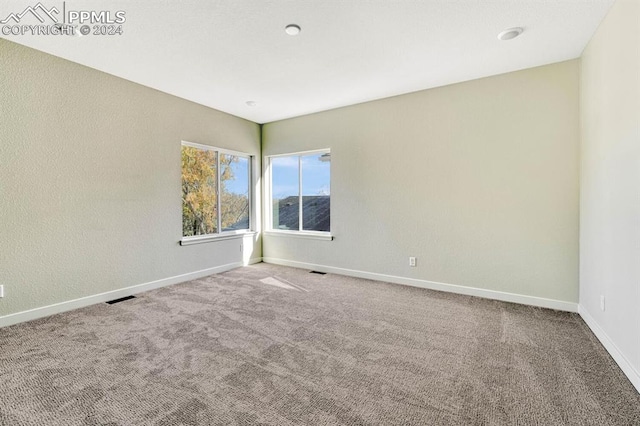 spare room featuring carpet, visible vents, and baseboards