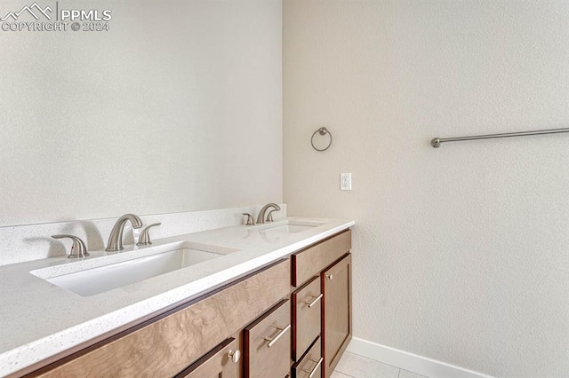 bathroom featuring double vanity, baseboards, a sink, and tile patterned floors