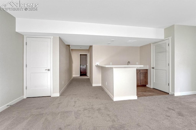 interior space featuring light carpet, baseboards, and indoor wet bar