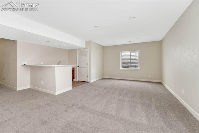 carpeted spare room featuring wet bar and baseboards