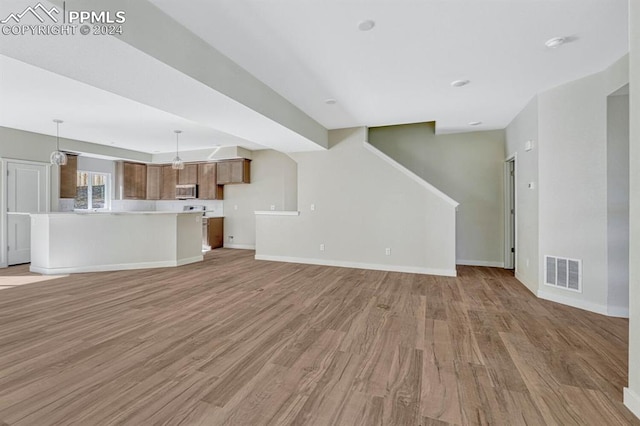 unfurnished living room featuring light wood-style flooring, visible vents, and baseboards