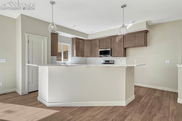 kitchen with tasteful backsplash, stainless steel microwave, and light wood-type flooring