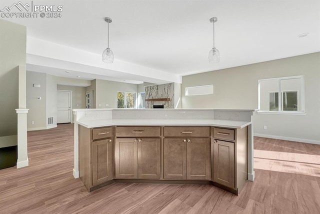 kitchen featuring open floor plan, light countertops, decorative light fixtures, and light wood-style floors