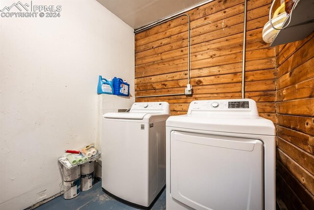 washroom with wood walls and washer and dryer