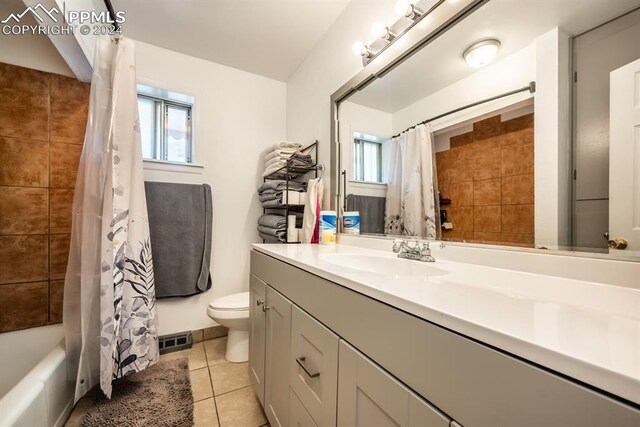 full bathroom featuring vanity, toilet, shower / bath combo with shower curtain, and tile patterned flooring