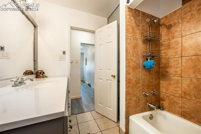 bathroom featuring tile patterned flooring, tiled shower / bath, and vanity