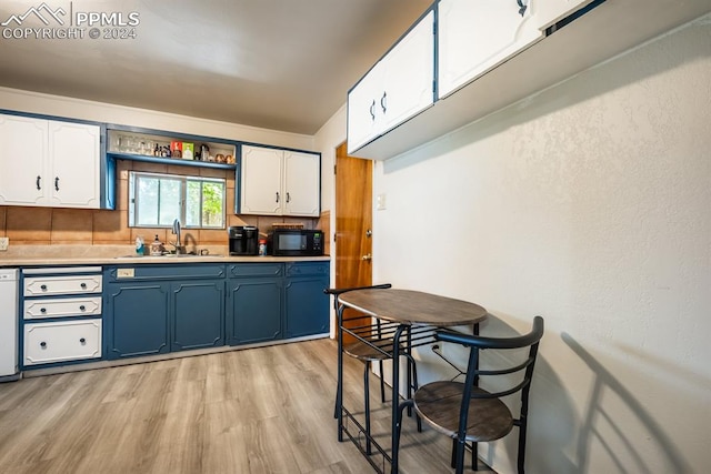 kitchen with white cabinets, blue cabinets, light hardwood / wood-style floors, and sink